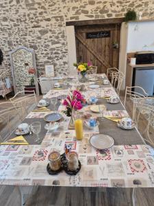 un tavolo con piatti e fiori sopra di Chambres d'hôtes LA GRANGE DU PA de LA GROLLE a Rocheservière Altre 18 foto