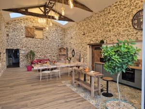 una cucina con un tavolo e un muro di pietra di Chambres d'hôtes LA GRANGE DU PA de LA GROLLE a Rocheservière