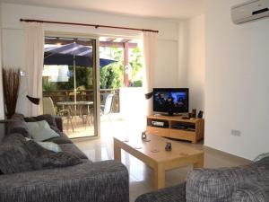 Una sala de estar con un sofá, un televisor y una mesa. en Vanessa 2 bedroom apartment, en Pafos