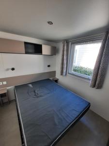 a bedroom with a bed in a room with a window at Mobil Home Charente-Maritime camping LA PIGNADE in La Tremblade