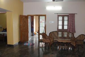 a living room with a table and chairs and a door at Royal Peters Holiday Homes, Main Falls, Coutralam in Kuttālam