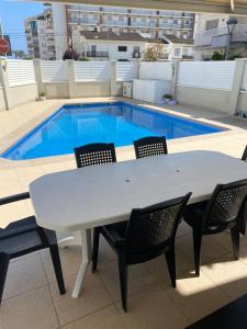 a white table and chairs in front of a swimming pool at House 50meters from the beach in Cunit