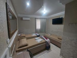 a hotel room with three beds and a television at Hotel Luar in Sao Paulo