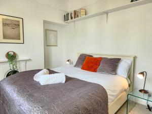 a bedroom with a bed with white sheets and orange pillows at Elegant 3BR Home Near Oxford Centre, Garden, WiFi in Oxford