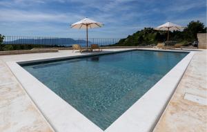 a swimming pool with two chairs and an umbrella at Nice Home In Slivno Ravno With Sauna in Slivno Ravno +40 photos
