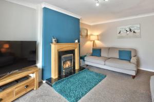 un salon avec un canapé et une cheminée dans l'établissement Riverview Cottage - North East Escapes, à Warkworth