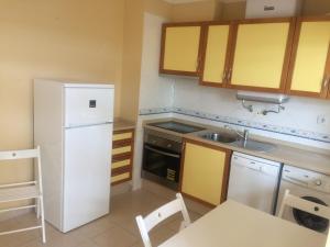 ヴィラモウラにあるMoura 11のキッチン(白い冷蔵庫、テーブル付)