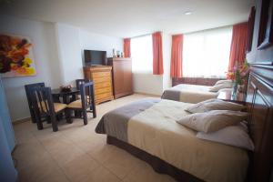 Banderas Suites في بوسيرياس: غرفة نوم بسريرين وطاولة ومكتب
