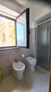 un bagno con un water, un lavandino e una finestra di Casa in Piazza a Cinquefrondi