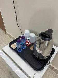 a tray with a tea kettle and cups on a table at شقق أثيل كراون المخدومة in Hafr Al-Batin