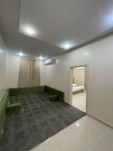 a living room with a green couch and a bedroom at شقق أثيل كراون المخدومة in Hafr Al-Batin +3 photos