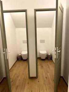 a bathroom with two toilets and two open doors at Les chambres du parc du Château in La Ferté-Saint-Aubin