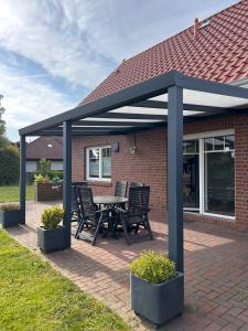 a pavilion with a table and chairs on a brick patio at Ferienhaus Meerträume in Pewsum