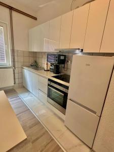 a kitchen with white cabinets and a refrigerator at Apartment Rea Ilidža 2 in Sarajevo