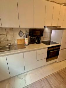 a kitchen with white cabinets and a sink and a microwave at Apartment Rea Ilidža 2 in Sarajevo