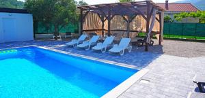 a swimming pool with chairs and a gazebo at Twins Land in Mostar