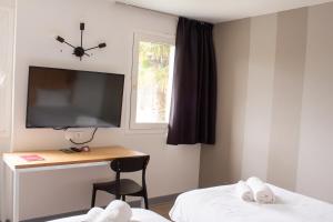 巴约讷Hôtel Les Genêts Bayonne的客房设有书桌、电视和椅子。