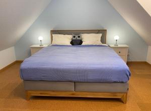 a large bed with a blue comforter and two lamps at 6010 Hollige 20 in Walsrode
