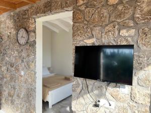a tv mounted to a stone wall with a clock at Linda House Corfu in Gastouri