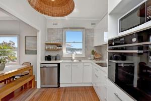 a kitchen with white cabinets and a sink at The Little Lake House Waterfront Escape in Rathmines