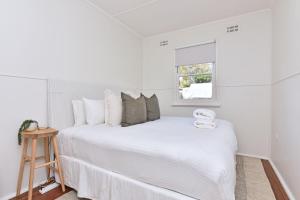 a white bedroom with a large bed and a window at The Little Lake House Waterfront Escape in Rathmines