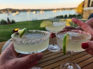 a person holding three wine glasses with lime slices in them at The Little Lake House Waterfront Escape in Rathmines +34 photos