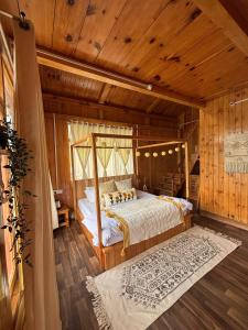 a bedroom with a bed in a room with wooden walls at Baserah - Stay & Cafe in Jibhi