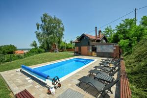 a swimming pool with chairs next to a house at Bakino brdo - Granny's hill in Bakovčica