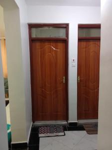 two wooden doors in a room with a mat at Leilani Homes in Kajiado