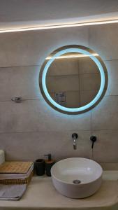 a bathroom with a sink and a round mirror at Elysium Sifnos in Artemonas +24 photos
