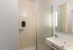 un bagno bianco con doccia e lavandino di B&B HOTEL Compiègne a Compiègne