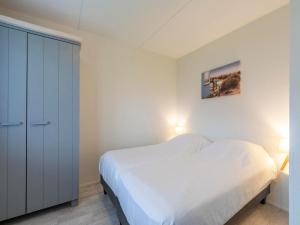 a white bedroom with a bed and a closet at Beach Apartment 7 for 4 guests in Callanstoog in Callantsoog