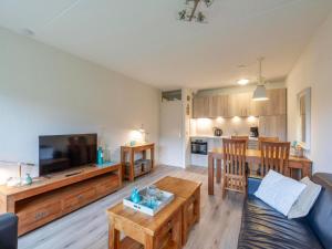 a living room with a couch and a tv and a kitchen at Beach Apartment 7 for 4 guests in Callanstoog in Callantsoog