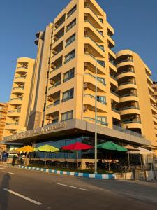 a large building with tables and umbrellas in front of it at Delmar Hotel Matrouh in Marsa Matruh