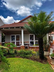 a palm tree in front of a house at Platinum Airport Lodge & Guesthouse in Pretoria