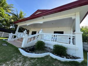 a white house with a white fence and a porch at Dahican Beach Homestay in Mati