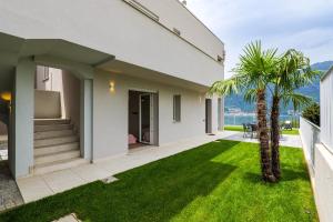 a house with a green lawn and palm trees at Spa Stella Lario in Lezzeno