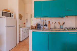 a kitchen with blue cabinets and a white refrigerator at Villa del sole 4 in Capoliveri +17 photos
