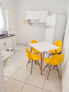 une cuisine avec une table blanche et des chaises jaunes dans l'établissement Studio urano 05 - Practicality, à Pirassununga