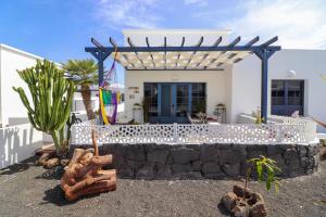 a white house with a stone wall and a pergola at Apartamento en Lanzarote Afrika Zen in Yaiza