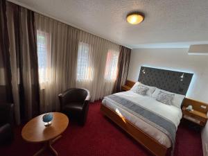 a hotel room with a bed and a chair at Hôtel des Trois Rois in Le Locle