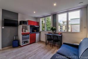 a kitchen with red cabinets and a table in a room at Appart hotel Cholet Carteron in Cholet