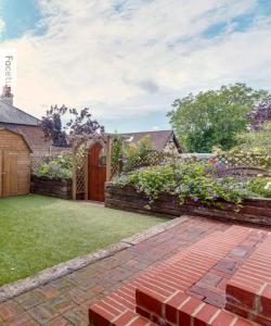 a garden with a brick walkway and a wooden gate at Charming Surrey Cottage perfect for Autumn or Winter gatherings in Great Bookham