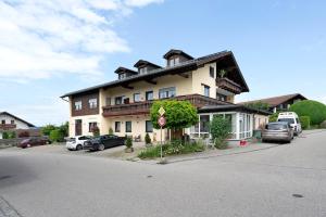una casa grande con coches estacionados frente a ella en Komfort Apartment Römersberger - 4, en Vogtareuth