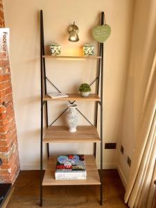 a book shelf with a vase and books on it at Charming Surrey Cottage perfect for Autumn or Winter gatherings in Great Bookham