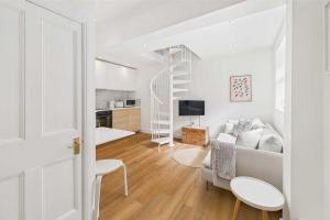 a white living room with a couch and a staircase at Host & Stay - The Surf Shack in Saltburn-by-the-Sea
