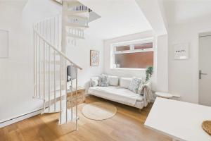 a white living room with a white couch and stairs at Host & Stay - The Surf Shack in Saltburn-by-the-Sea +10 photos