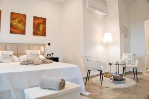 a white bedroom with a bed and two chairs at Tenuta Poggio Piero in Montemassi