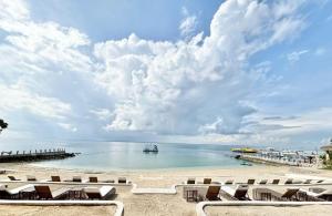 a beach with chairs and a boat in the water at One Manchester Place Mactan Newtown in Lapu Lapu City