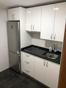 a small kitchen with white cabinets and a refrigerator at El apartamento de la catedral in Burgos +9 photos